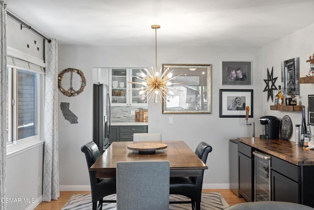 dining space featuring wine cooler, a chandelier, and light wood-type flooring