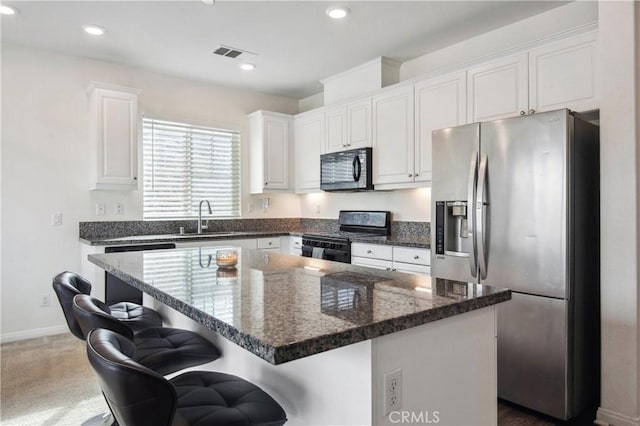 kitchen with a kitchen bar, sink, black appliances, a center island, and white cabinets