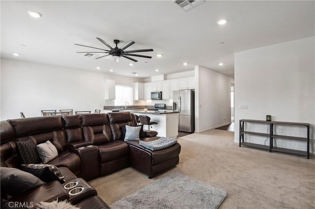 living room with sink, light colored carpet, and ceiling fan