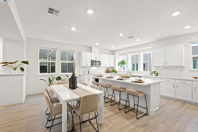 kitchen featuring a center island, sink, light hardwood / wood-style flooring, and white cabinets