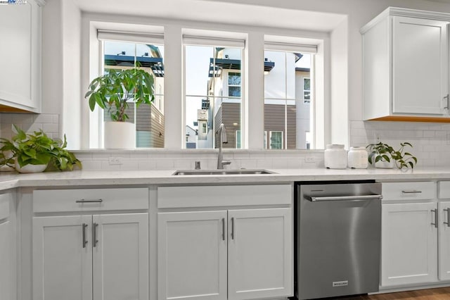 kitchen featuring sink, backsplash, stainless steel dishwasher, and white cabinets