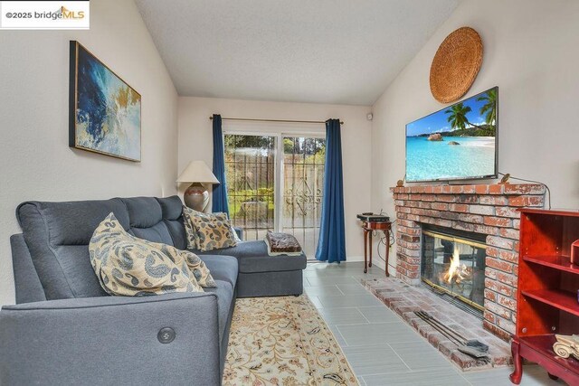 tiled living room with lofted ceiling, a textured ceiling, and a fireplace