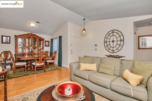 living room with vaulted ceiling, hardwood / wood-style floors, and a textured ceiling