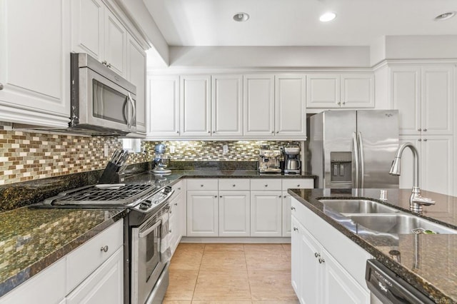 kitchen featuring stainless steel appliances, white cabinets, and dark stone counters