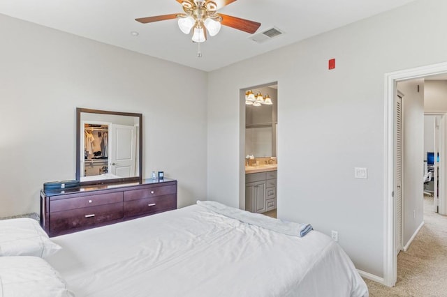 carpeted bedroom with ensuite bath, baseboards, visible vents, and ceiling fan