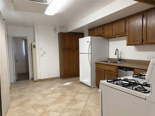 kitchen featuring white appliances, brown cabinets, a sink, and baseboards