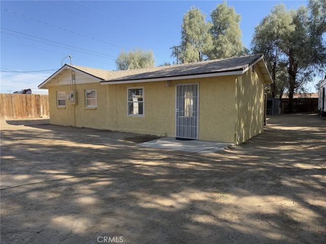 back of property with a shingled roof, a patio area, fence, and stucco siding