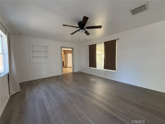 spare room featuring visible vents, dark wood finished floors, and baseboards