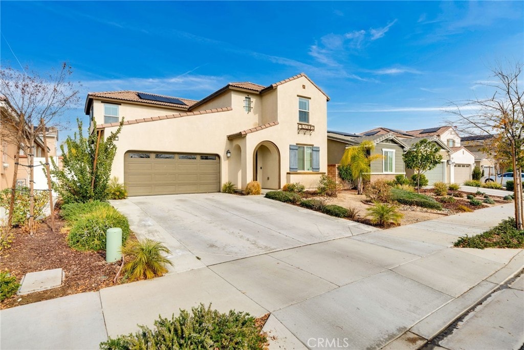 mediterranean / spanish-style home featuring a garage and solar panels