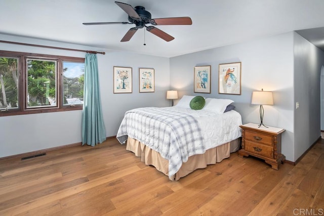 bedroom with baseboards, a ceiling fan, visible vents, and light wood-style floors