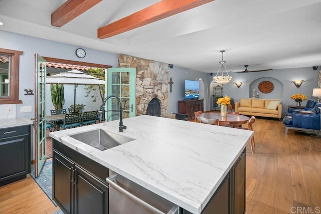 kitchen featuring a sink, light wood-type flooring, open floor plan, and stainless steel dishwasher