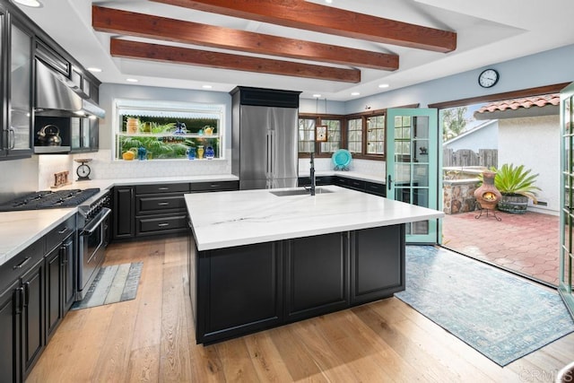 kitchen featuring dark cabinets, light wood-style flooring, wall chimney exhaust hood, and high quality appliances