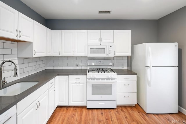 kitchen with white appliances, visible vents, light wood-style flooring, white cabinetry, and a sink