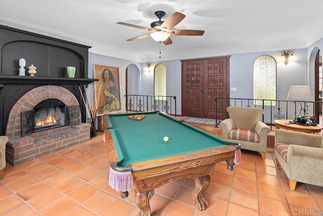 recreation room with a ceiling fan, arched walkways, a fireplace, and tile patterned floors