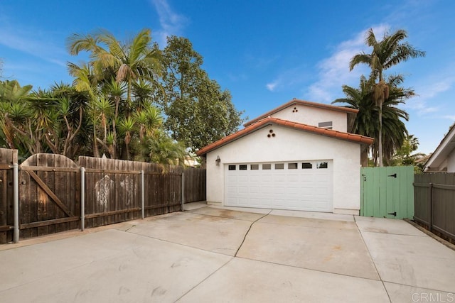 garage with a gate, fence, and concrete driveway