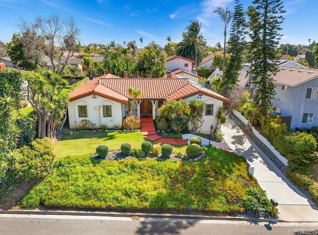 mediterranean / spanish-style home featuring a tile roof, a front lawn, and stucco siding