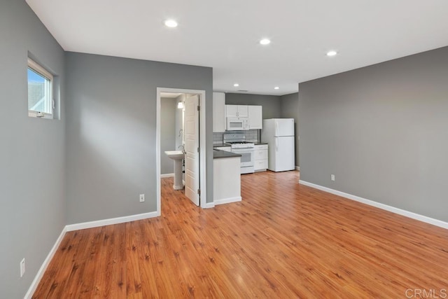 unfurnished living room with light wood finished floors, baseboards, and recessed lighting