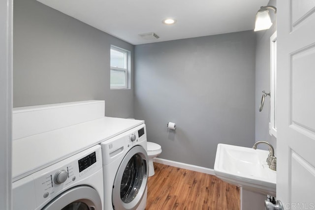 washroom with light wood-style floors, washing machine and dryer, a sink, laundry area, and baseboards