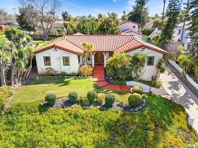 mediterranean / spanish-style house with driveway, stucco siding, a front yard, and a tiled roof