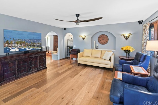 living room featuring ceiling fan, arched walkways, and wood finished floors