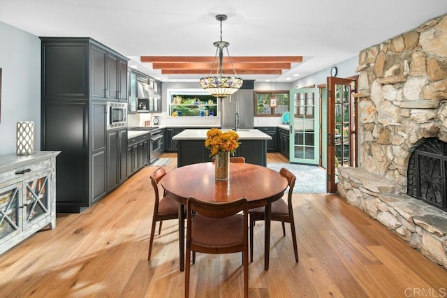 dining room with light wood finished floors and a stone fireplace