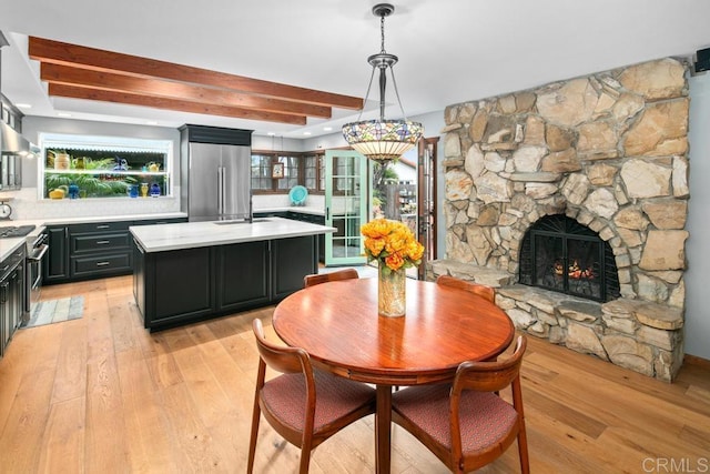 dining room with light wood finished floors, a fireplace, and beam ceiling