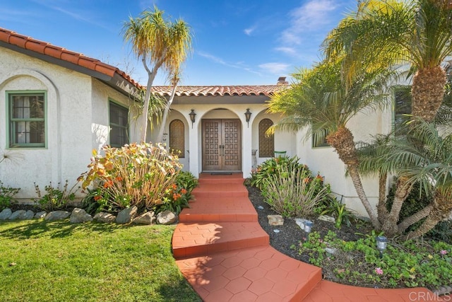 doorway to property featuring a tiled roof, french doors, and stucco siding