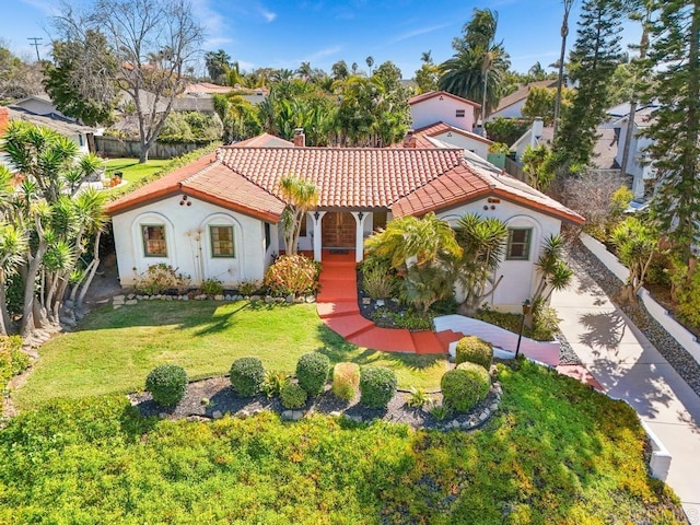 mediterranean / spanish-style house featuring a front yard, a tile roof, and stucco siding