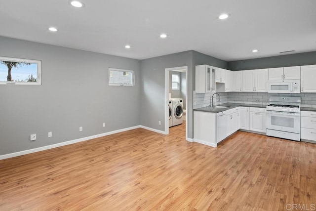 kitchen with dark countertops, decorative backsplash, a sink, white appliances, and independent washer and dryer