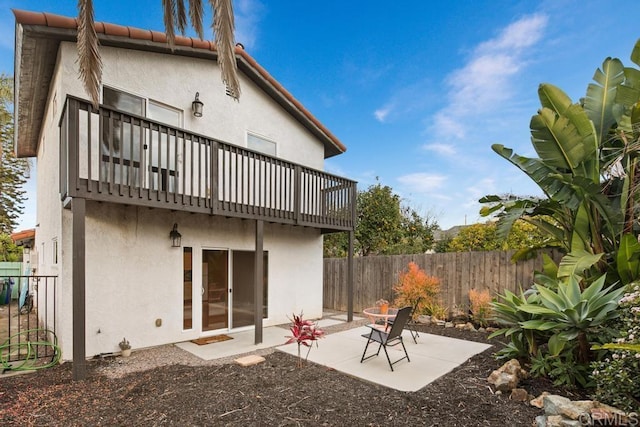 rear view of house featuring a patio area, a tile roof, fence, and stucco siding