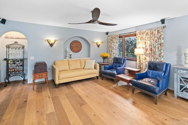 living area with light wood-style floors, ceiling fan, and baseboards