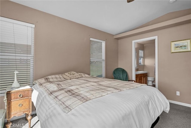 bedroom featuring lofted ceiling, carpet, ensuite bath, and baseboards