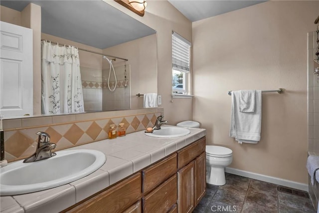 full bath featuring toilet, a tile shower, decorative backsplash, and a sink