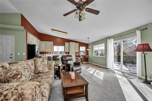 living area featuring light carpet, vaulted ceiling, baseboards, and ceiling fan