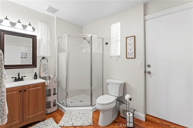 bathroom featuring visible vents, a shower stall, vanity, and wood finished floors