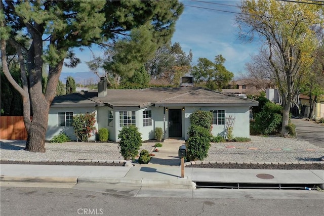 single story home featuring a chimney, a tile roof, and stucco siding