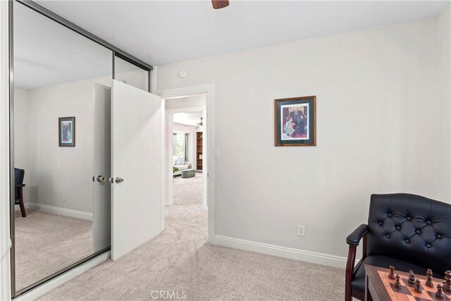 living area featuring light carpet and ceiling fan