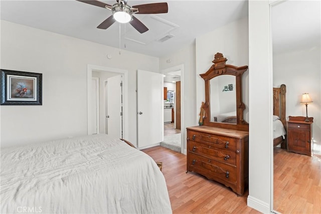 bedroom with attic access, visible vents, ceiling fan, and light wood finished floors