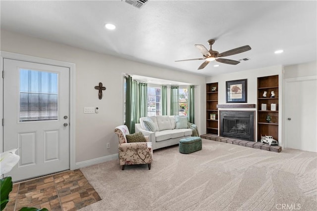 carpeted living area with a fireplace with raised hearth, baseboards, visible vents, and recessed lighting