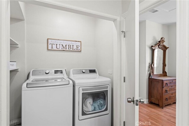 laundry area with light hardwood / wood-style flooring and washing machine and dryer