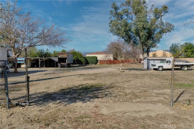 view of yard with fence, a carport, and an outdoor structure