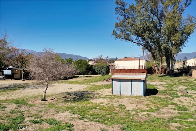view of yard featuring an outbuilding, a mountain view, and fence