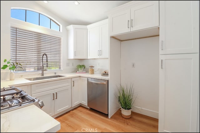 kitchen featuring white cabinetry, sink, stove, stainless steel dishwasher, and light hardwood / wood-style flooring