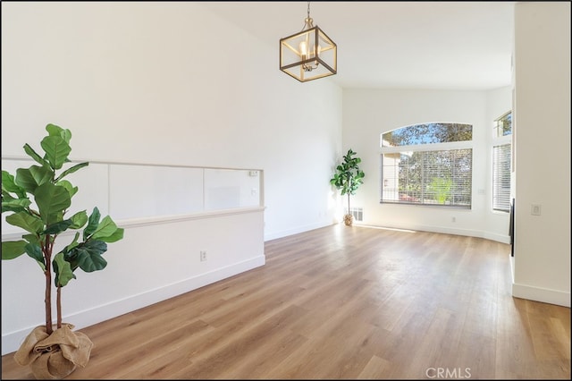 interior space featuring wood-type flooring, a chandelier, and vaulted ceiling