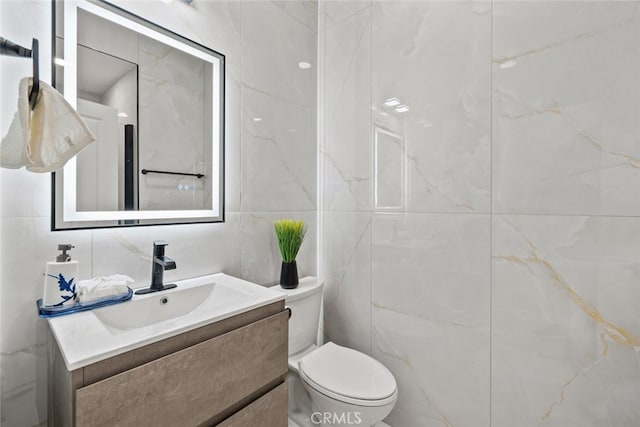 bathroom featuring vanity, toilet, and tile walls