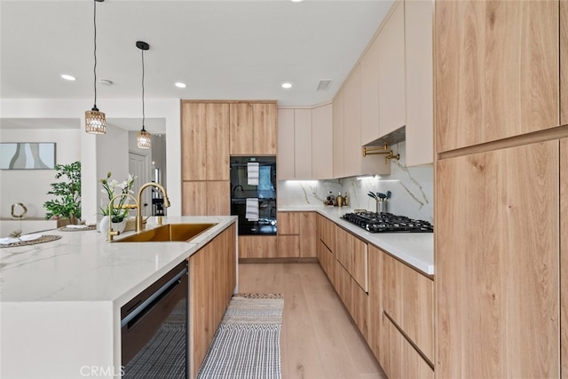 kitchen with sink, white cabinetry, light brown cabinets, light stone countertops, and black appliances