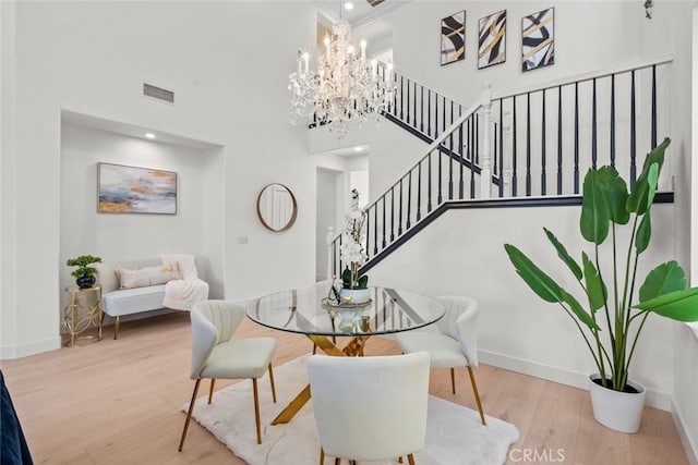 dining room featuring a high ceiling, a notable chandelier, and light hardwood / wood-style flooring