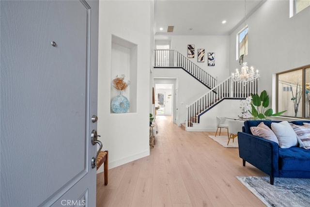 entrance foyer with a notable chandelier, light hardwood / wood-style flooring, ornamental molding, and a high ceiling