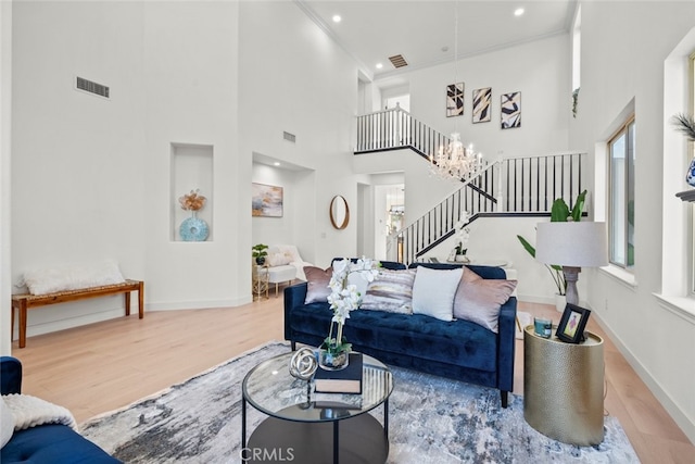 living room featuring light hardwood / wood-style floors, a chandelier, and a high ceiling