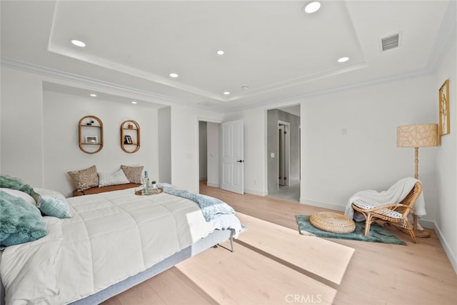 bedroom with a tray ceiling, ornamental molding, and light wood-type flooring